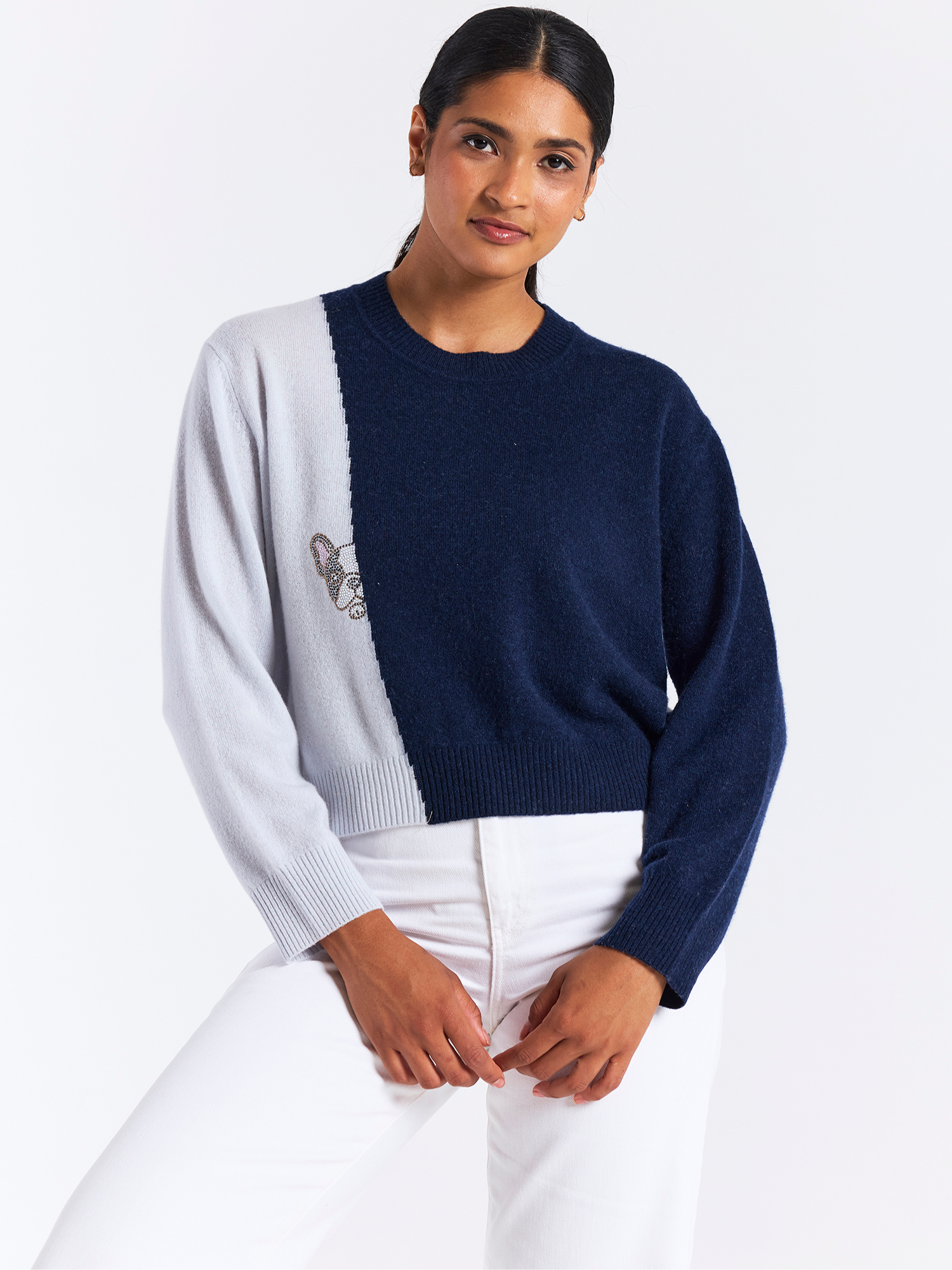 Person wearing a two-tone sweater with white and navy sections on a plain background