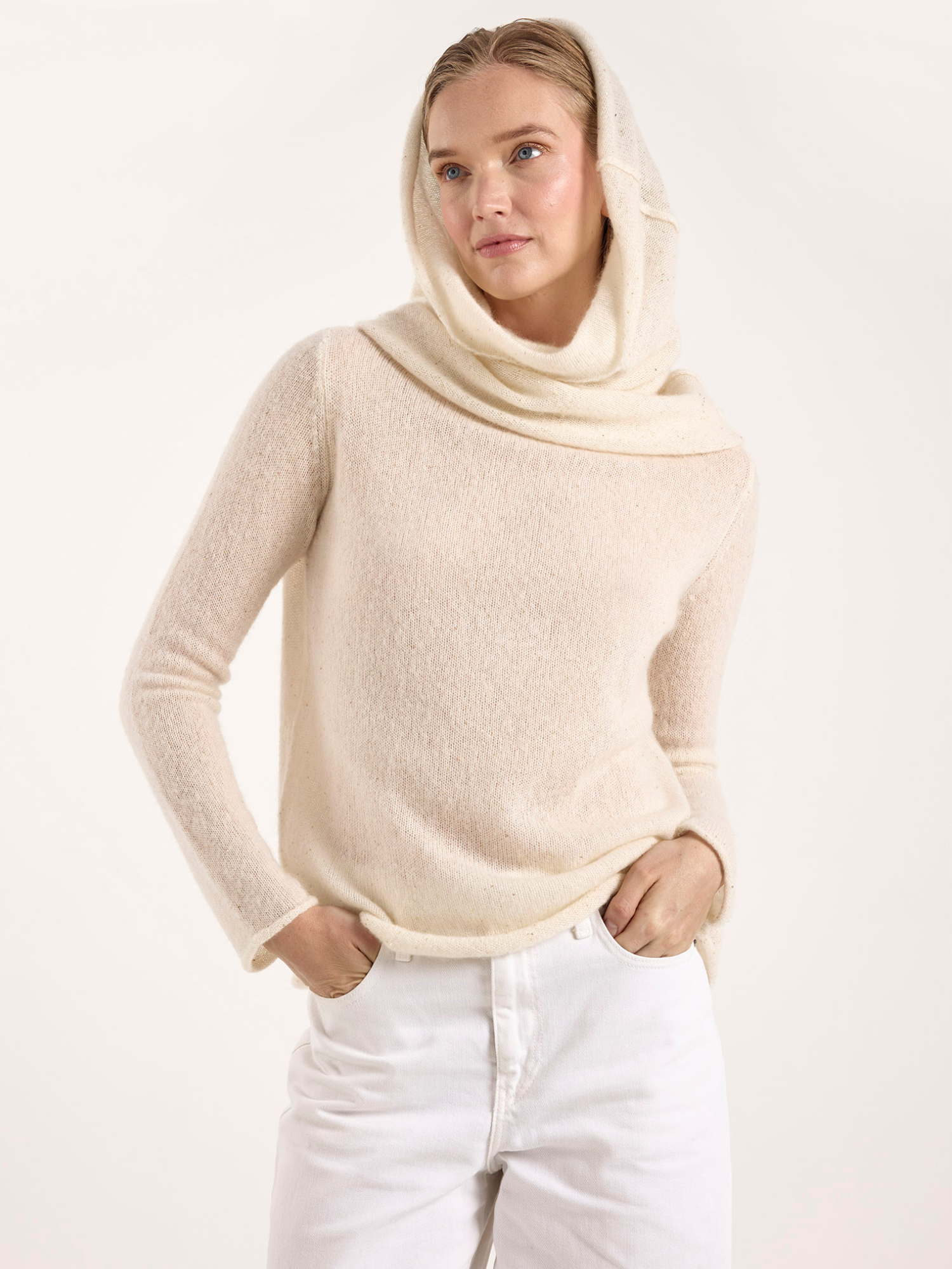 Woman wearing a beige sweater with a hood against a white background