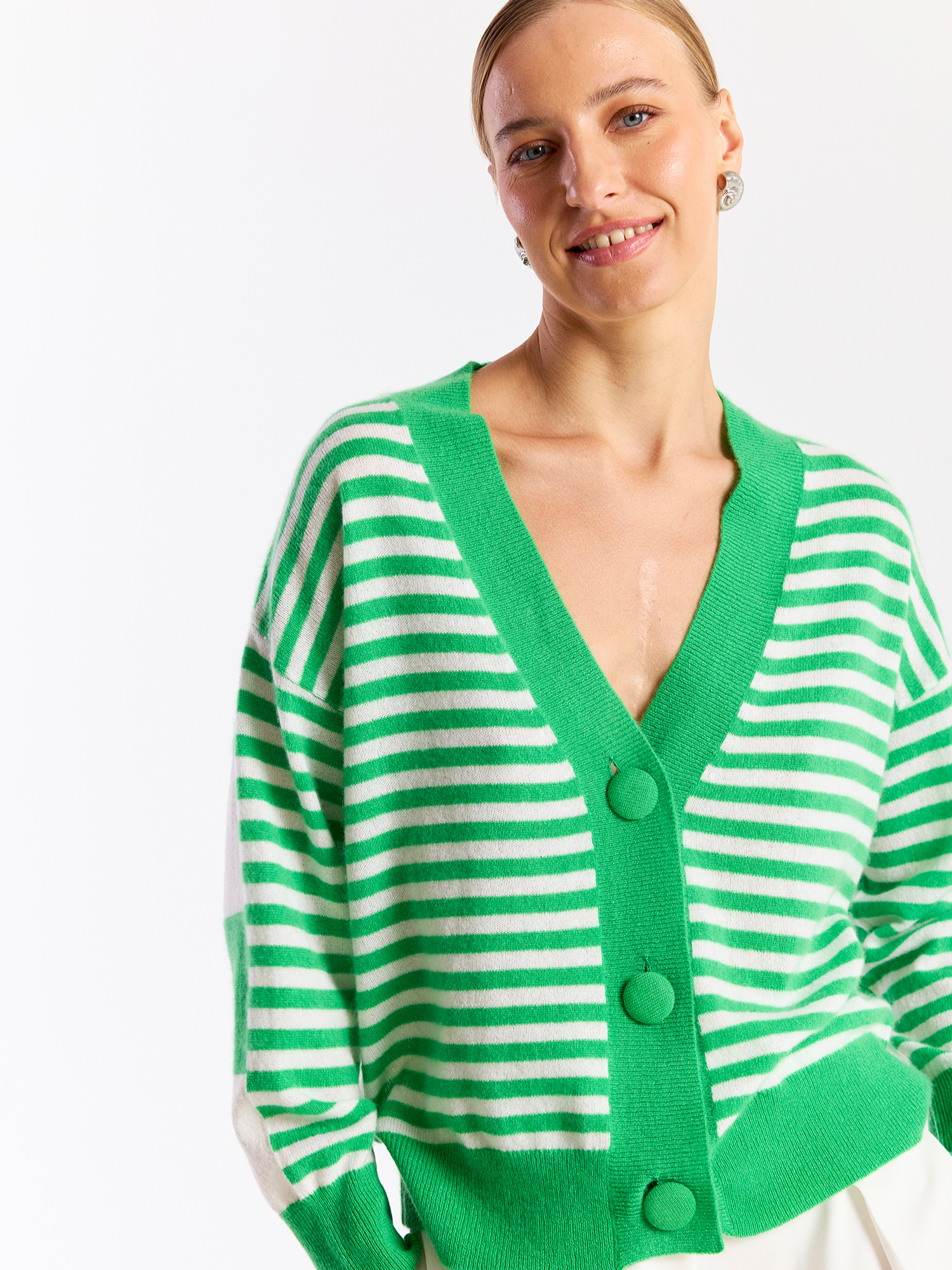 Woman wearing a green and white striped cardigan on a white background