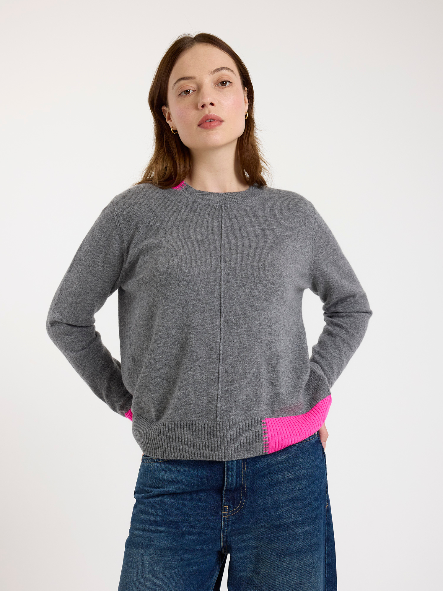 Woman wearing a grey sweater with pink trim on a white background