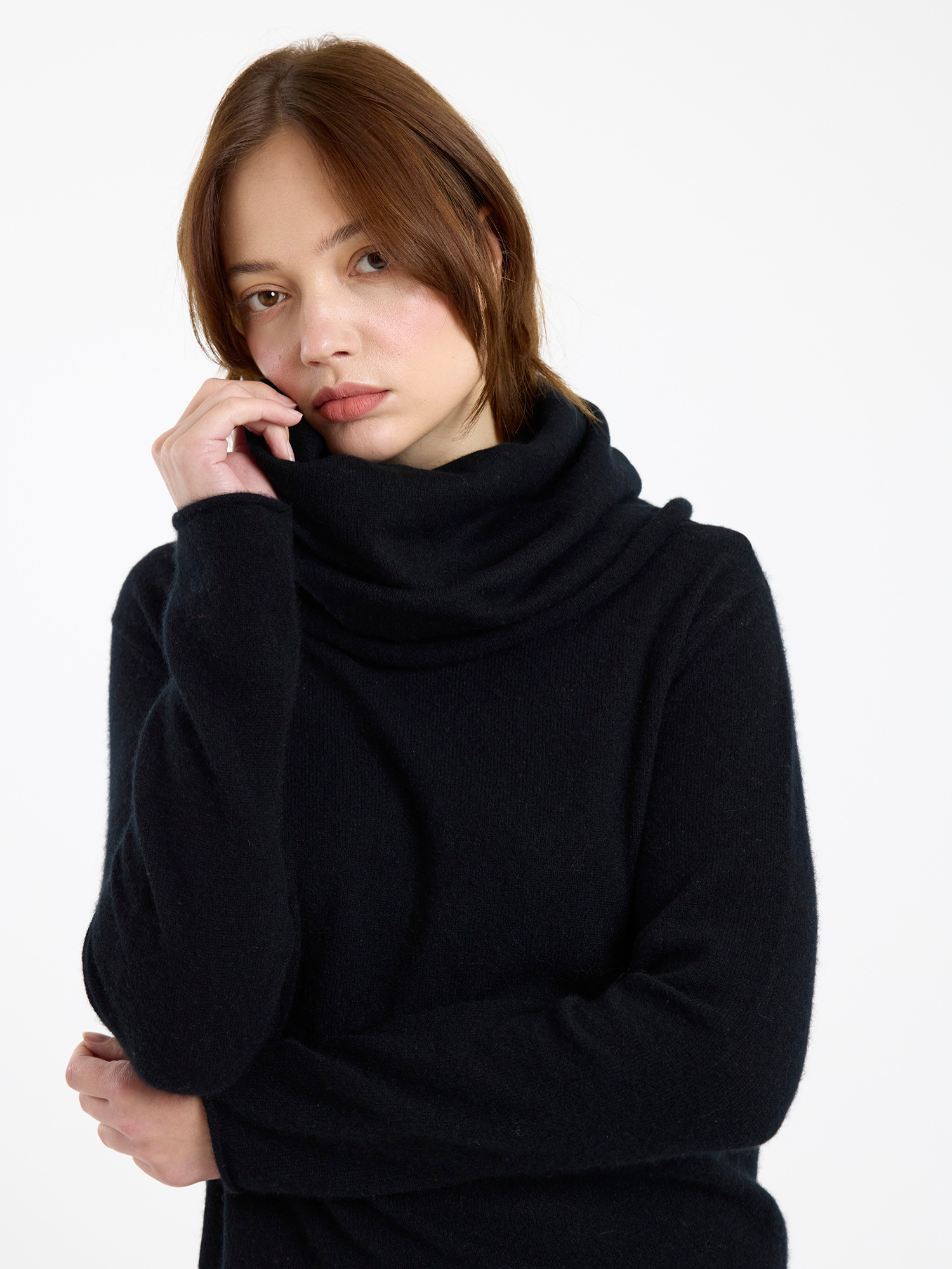 Woman wearing a black cowlneck sweater on a white background