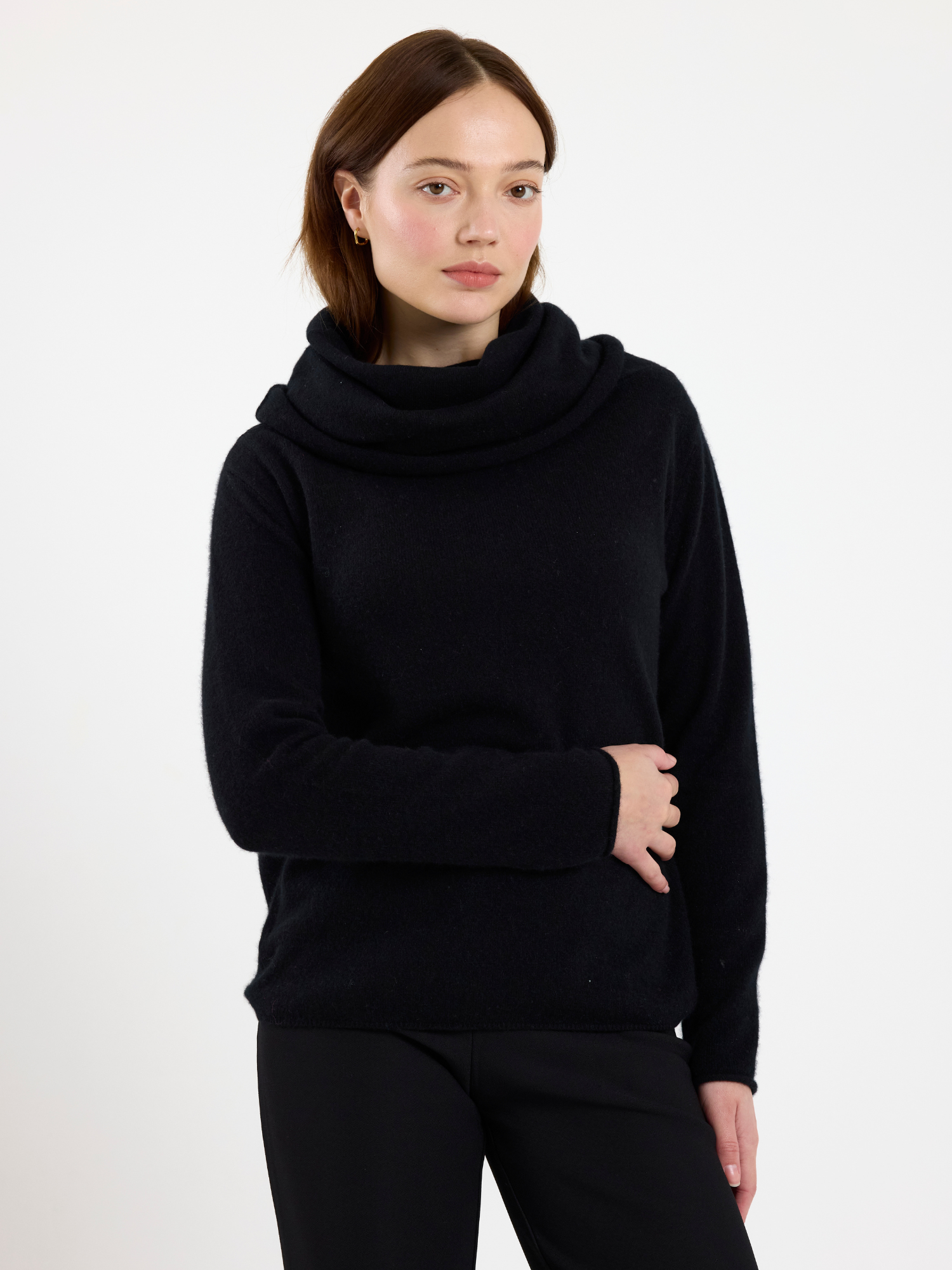 Woman wearing a black cowl-neck sweater on a white background