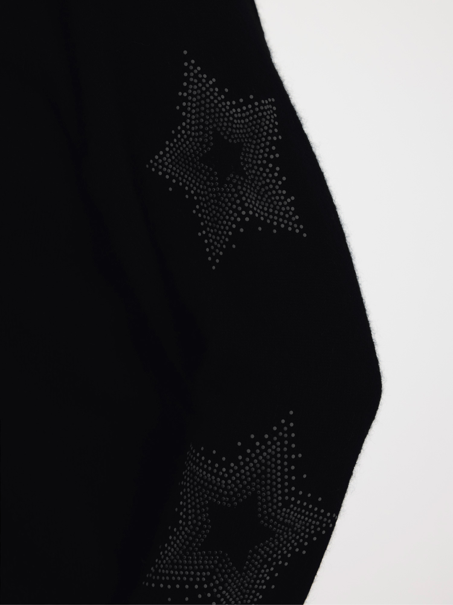 Woman wearing a black sweater with subtle star design on the sleeves 