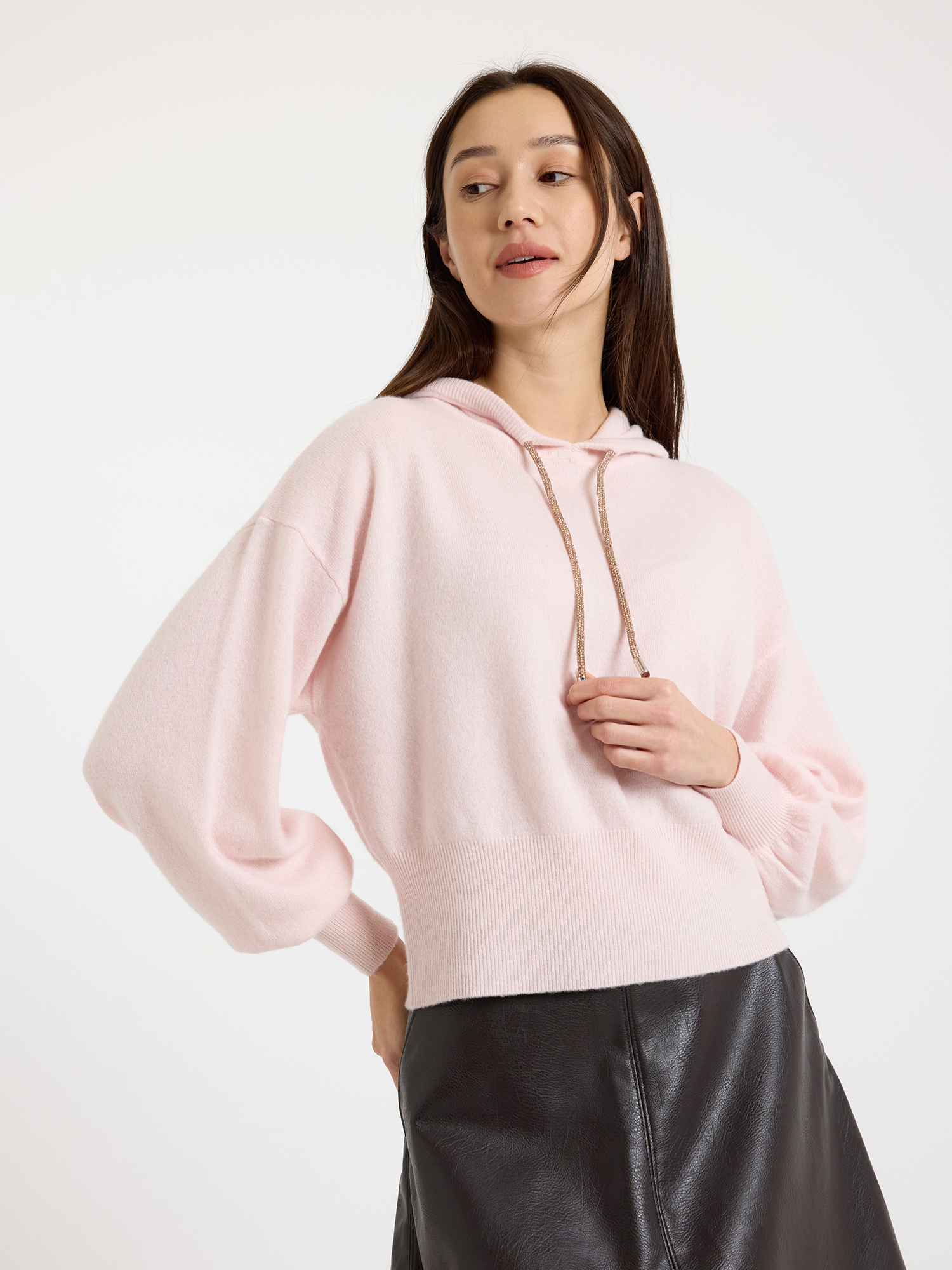 Woman wearing a light pink hoodie against a white background