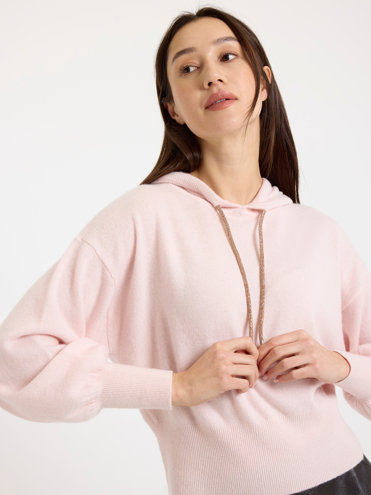 Woman wearing a light pink hoodie against a white background