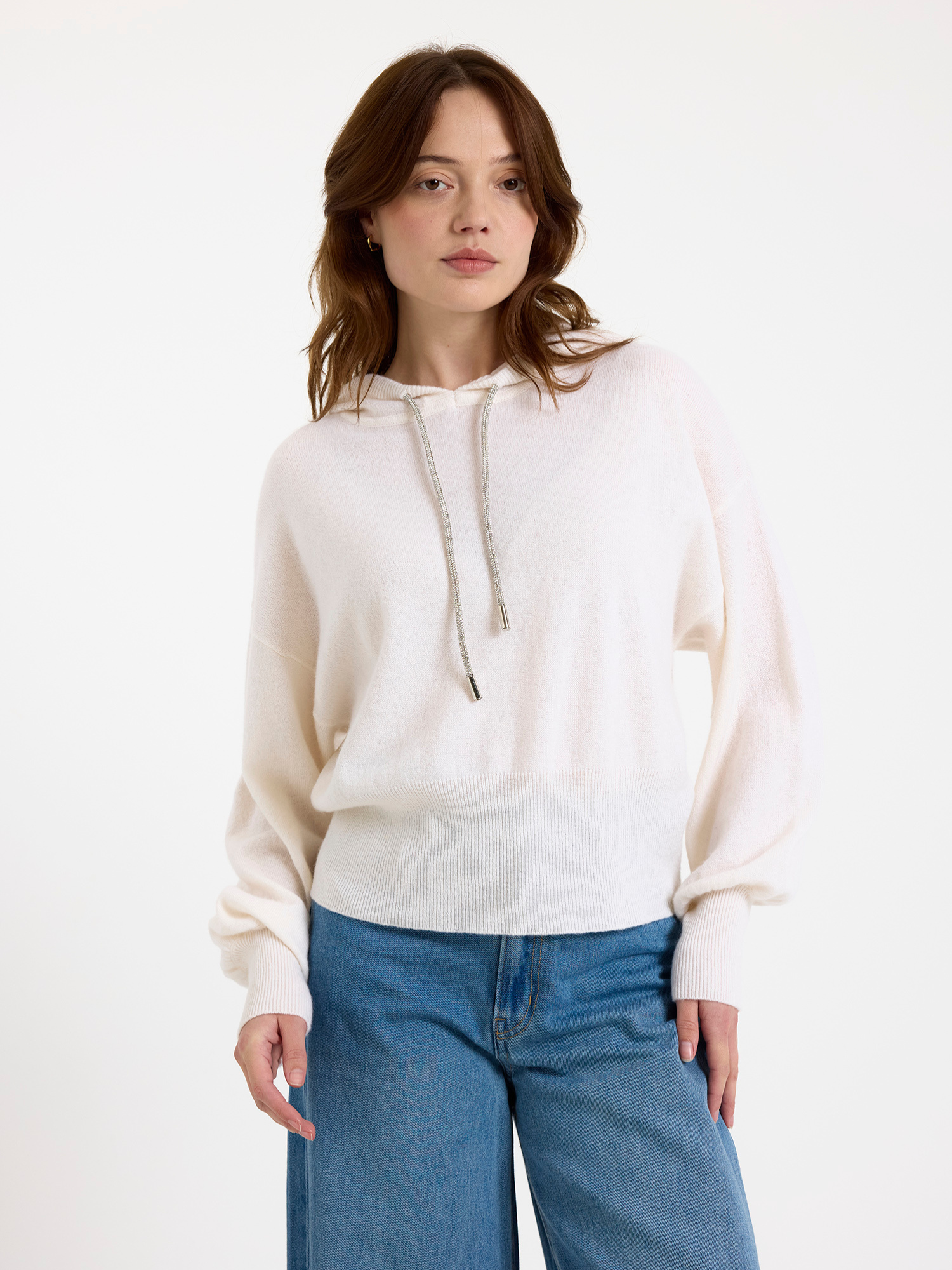 Woman wearing a white hoodie and blue jeans on a white background