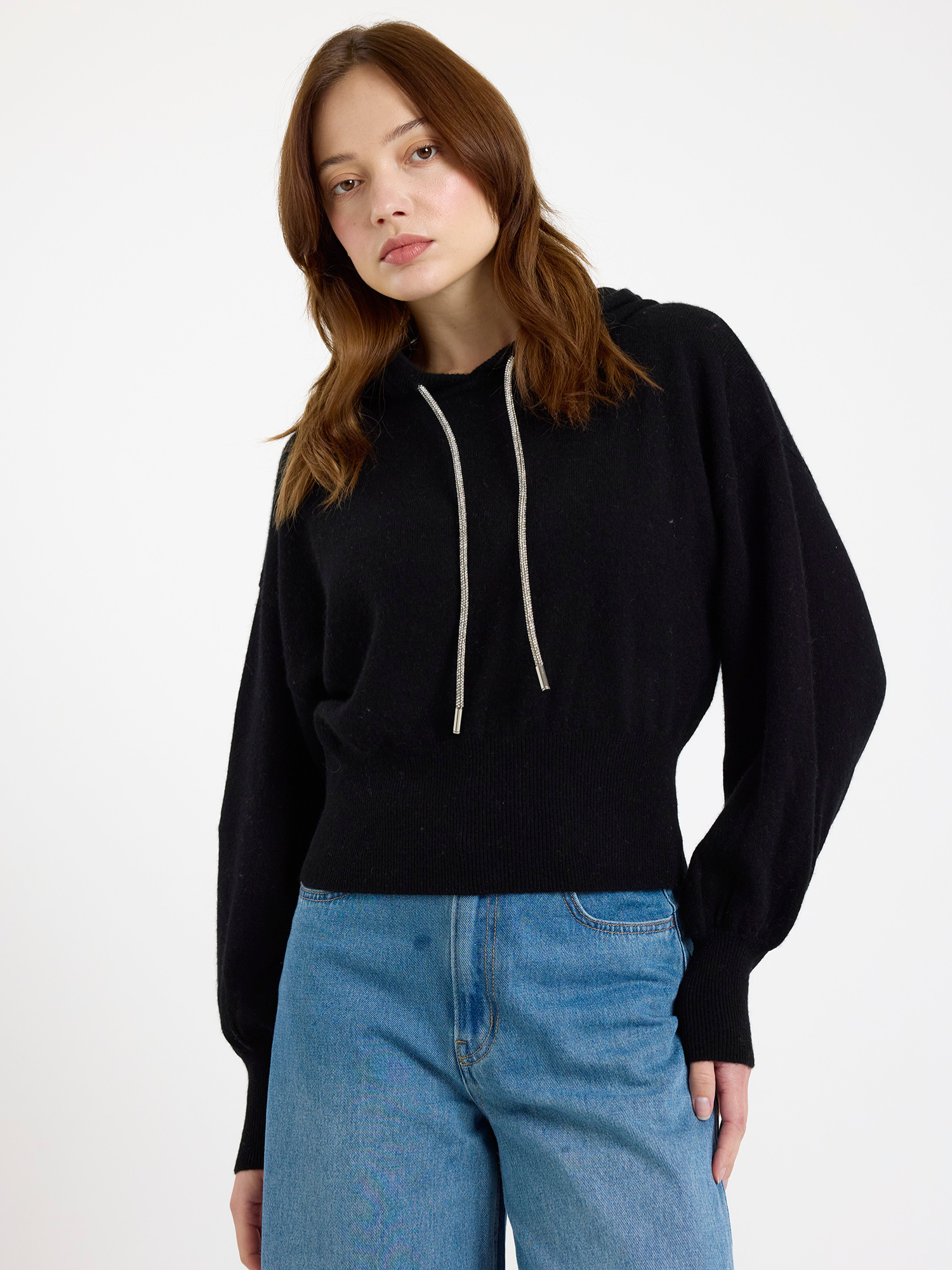 Woman wearing a black hoodie and blue jeans on a white background