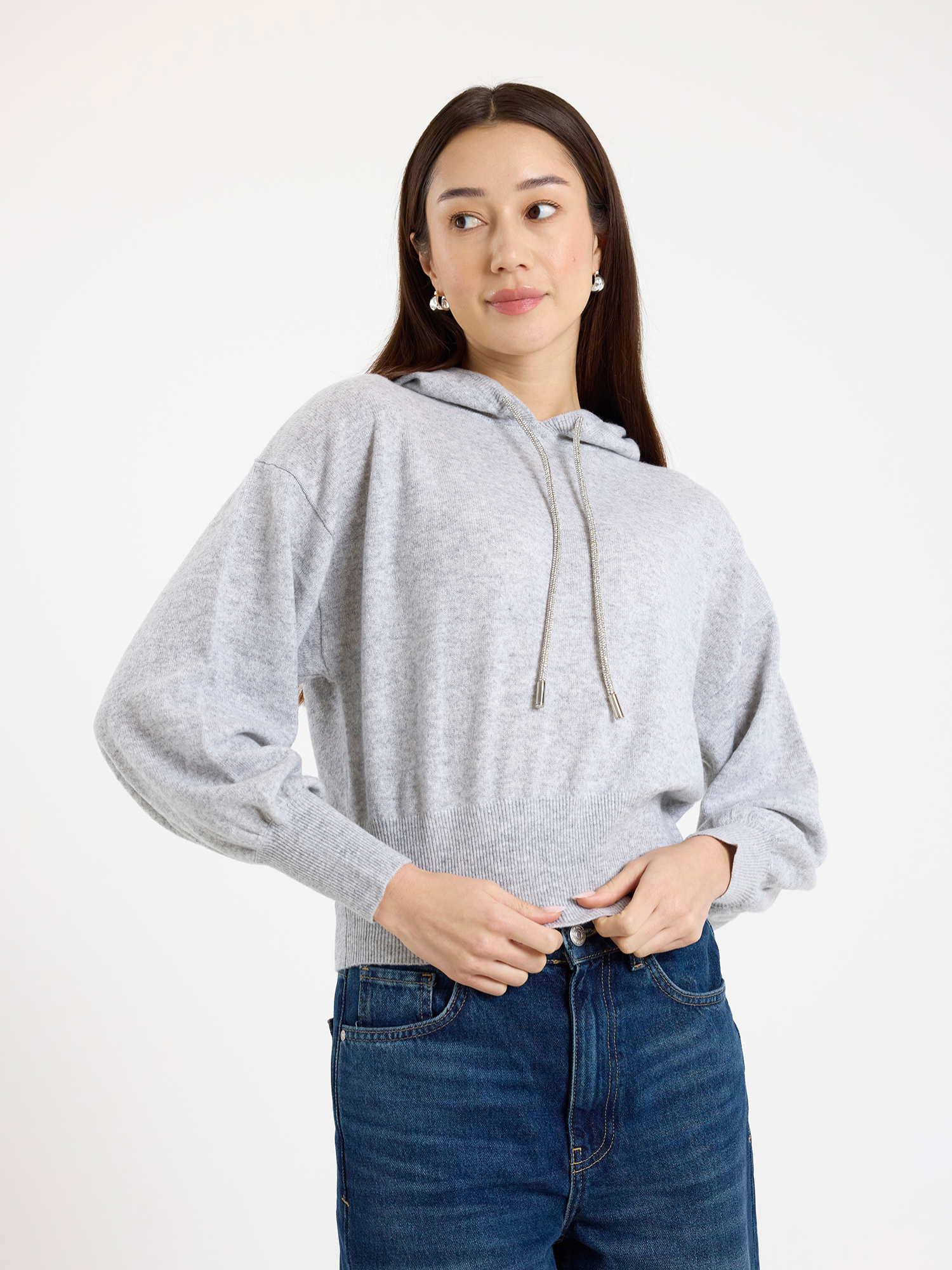 Woman wearing a grey hoodie and blue jeans on a white background