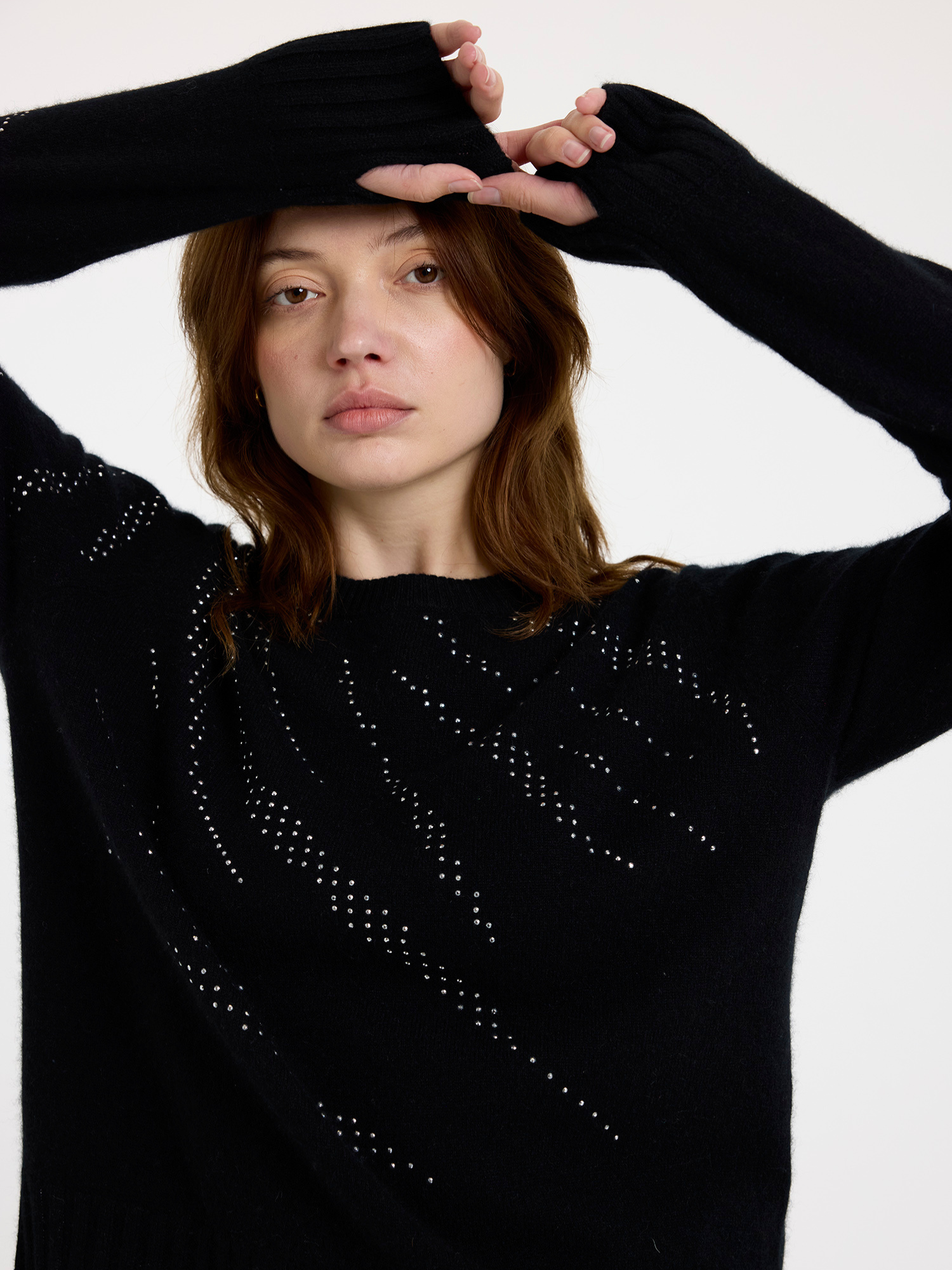 Woman wearing a black sweater with silver stud zebra patterns against a white background