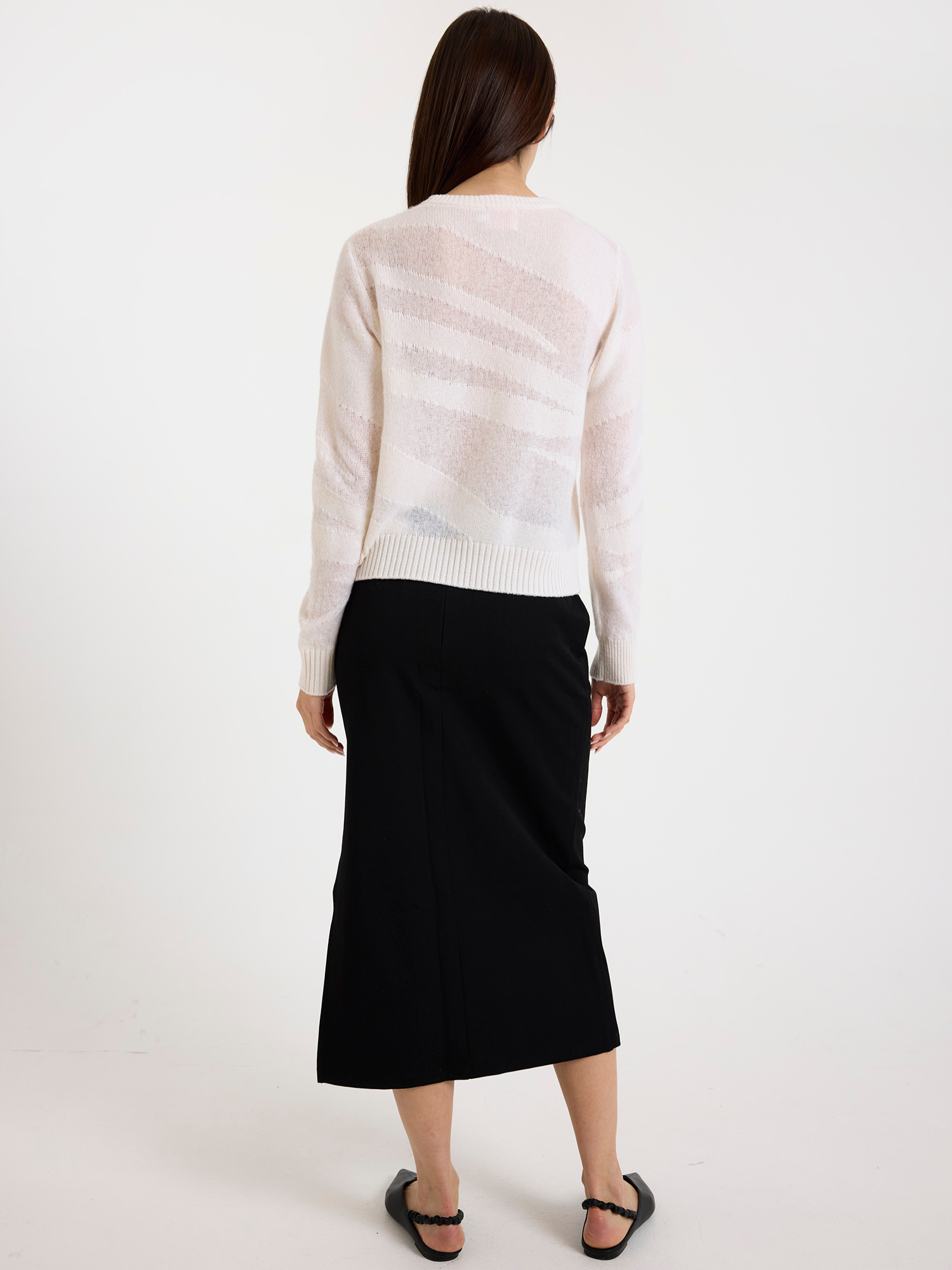 Woman wearing a white zebra detail sweater and black skirt against a white background