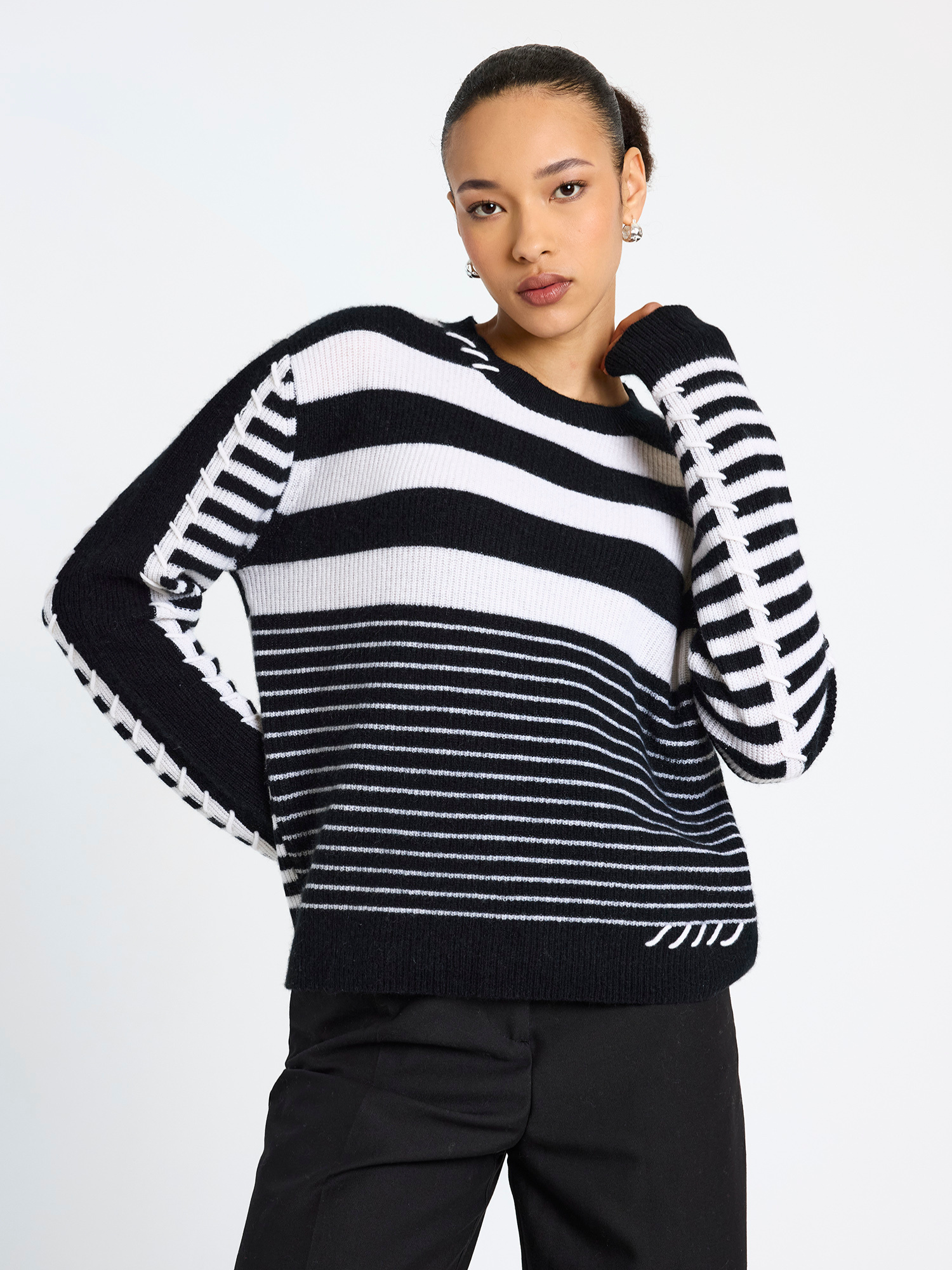 Woman wearing a black and white striped sweater on a plain background