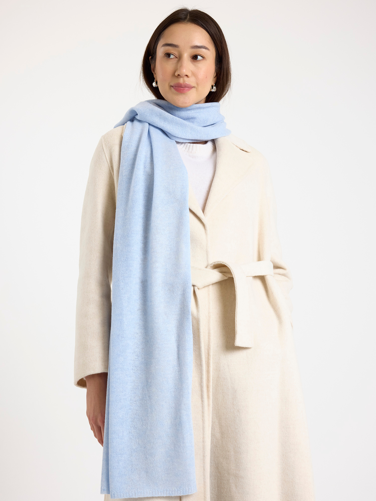 Woman wearing a light blue scarf and beige coat on a white background
