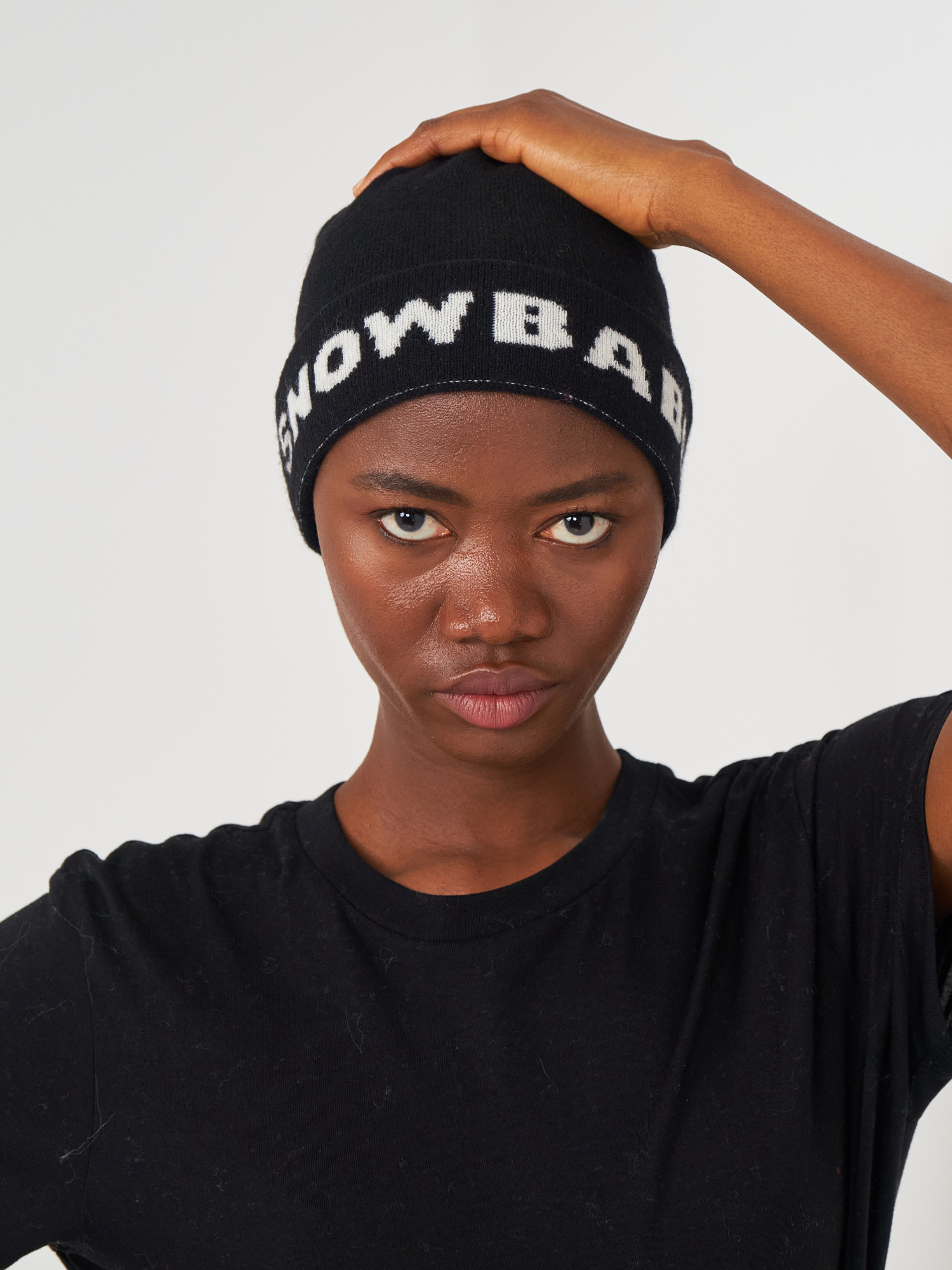 Person wearing a black beanie with 'Snow Babe' text against a white background