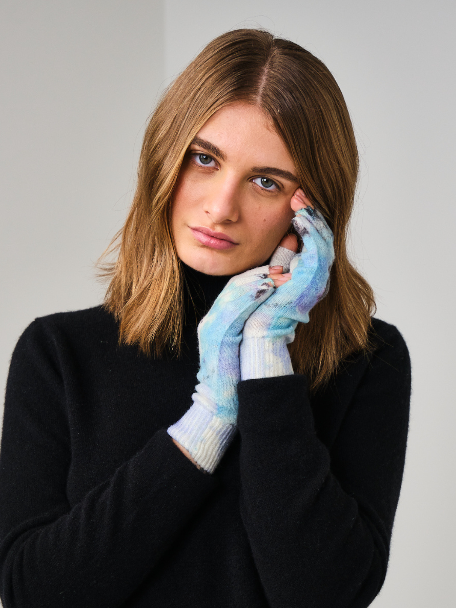 Woman wearing colorful gloves against a plain background