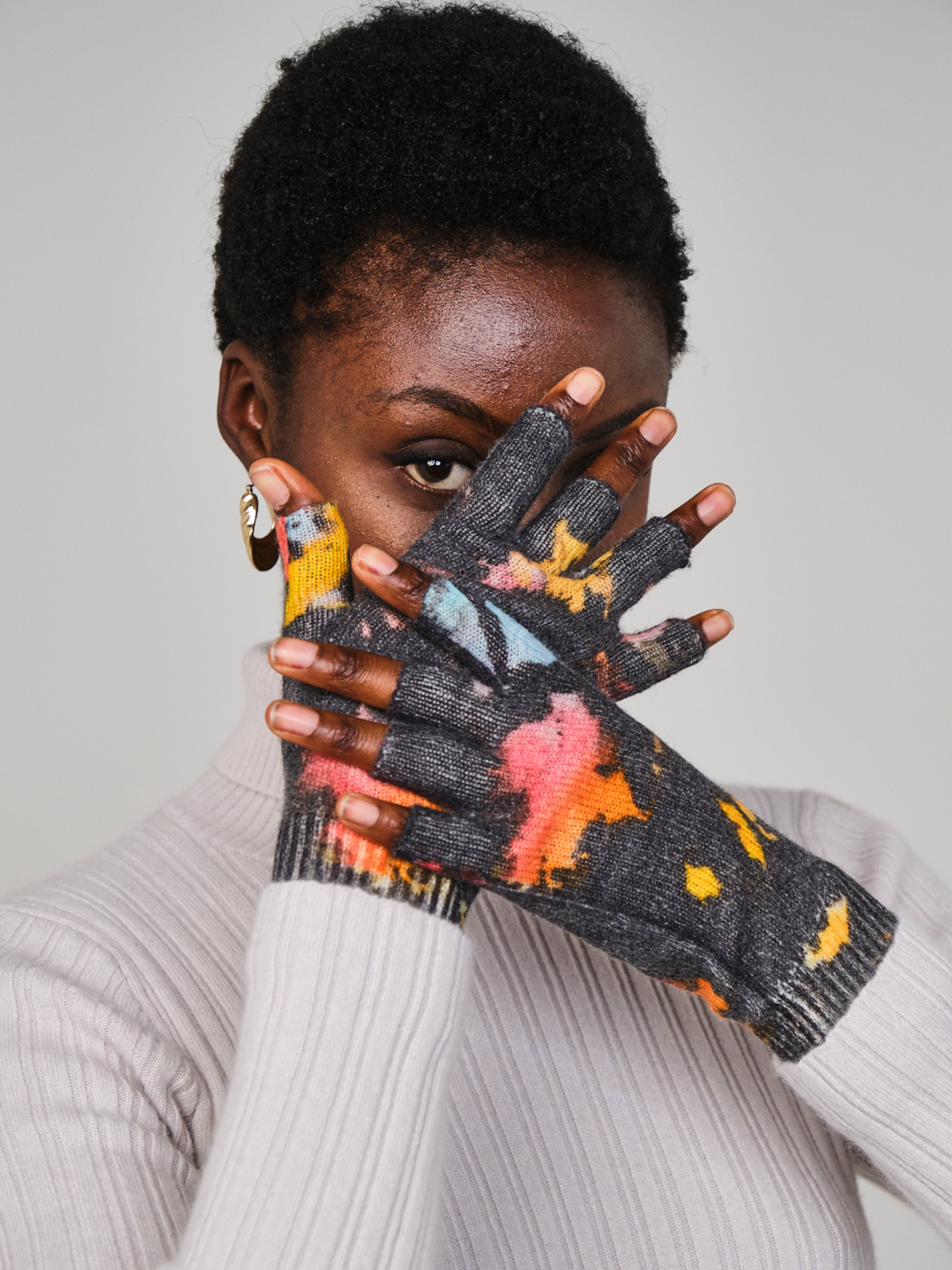 Person wearing colorful patterned gloves with a neutral background