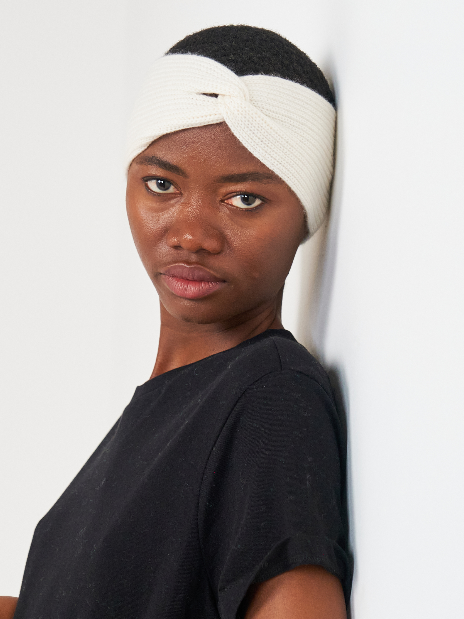 Woman wearing a white headband against a plain background