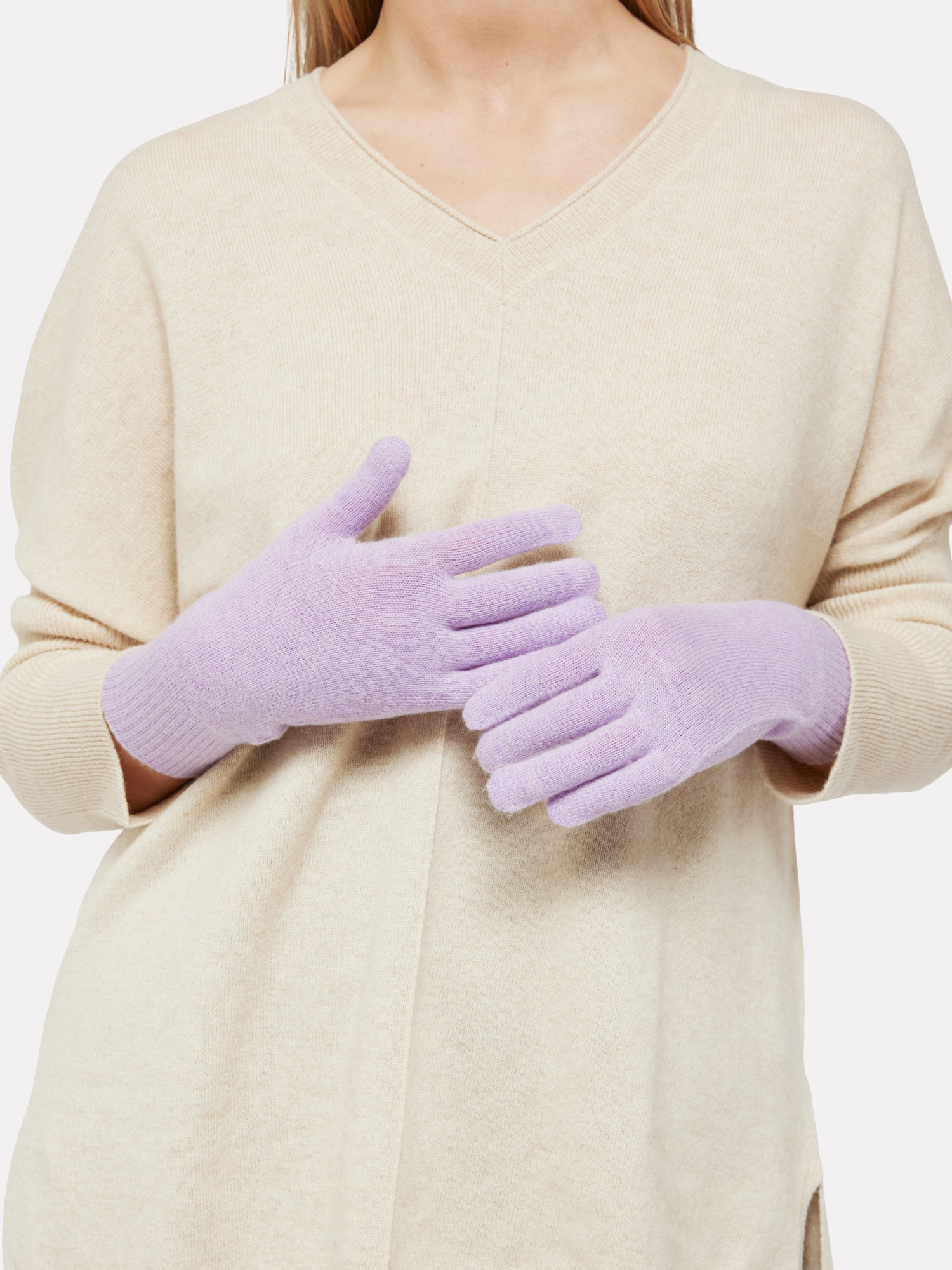 Person wearing light purple gloves with a beige sweater on a white background
