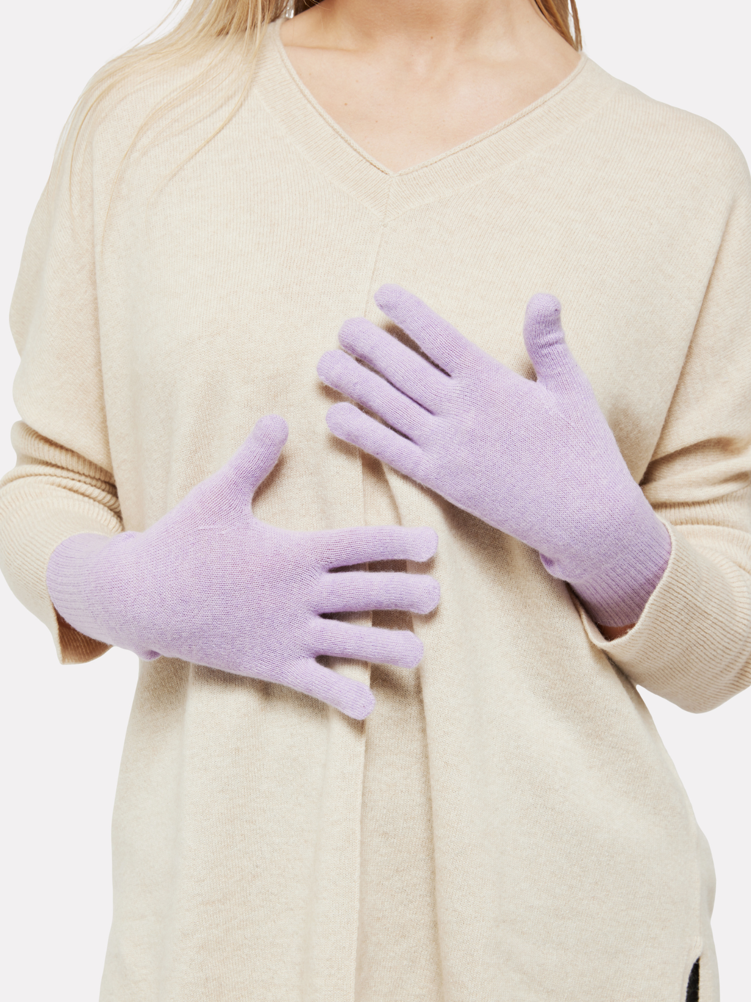 Person wearing light purple gloves with a beige sweater on a white background